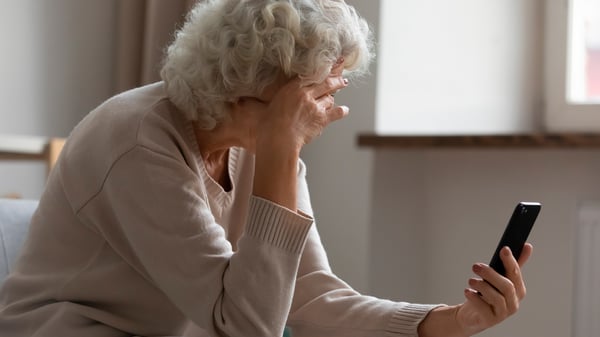 eldery woman looking at phone online banking frustrated